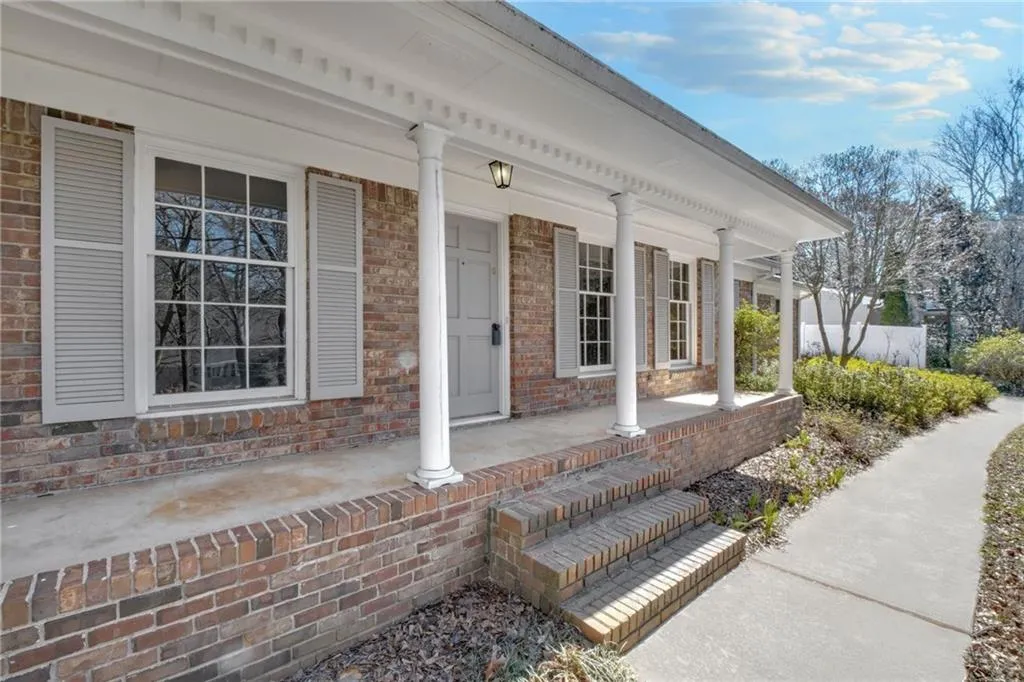 Doorway to property featuring covered porch and brick siding