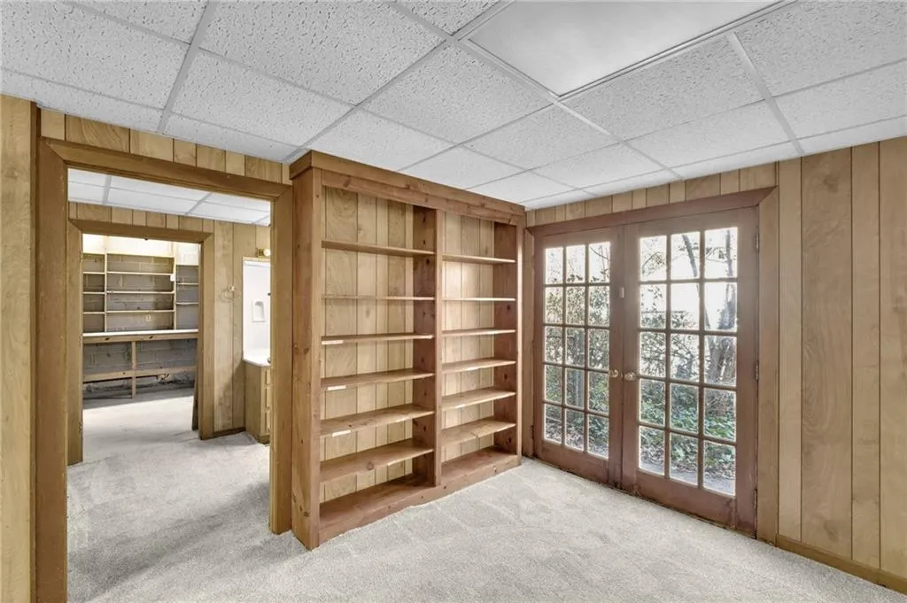 Unfurnished room featuring a wealth of natural light, french doors, light carpet, and wooden walls