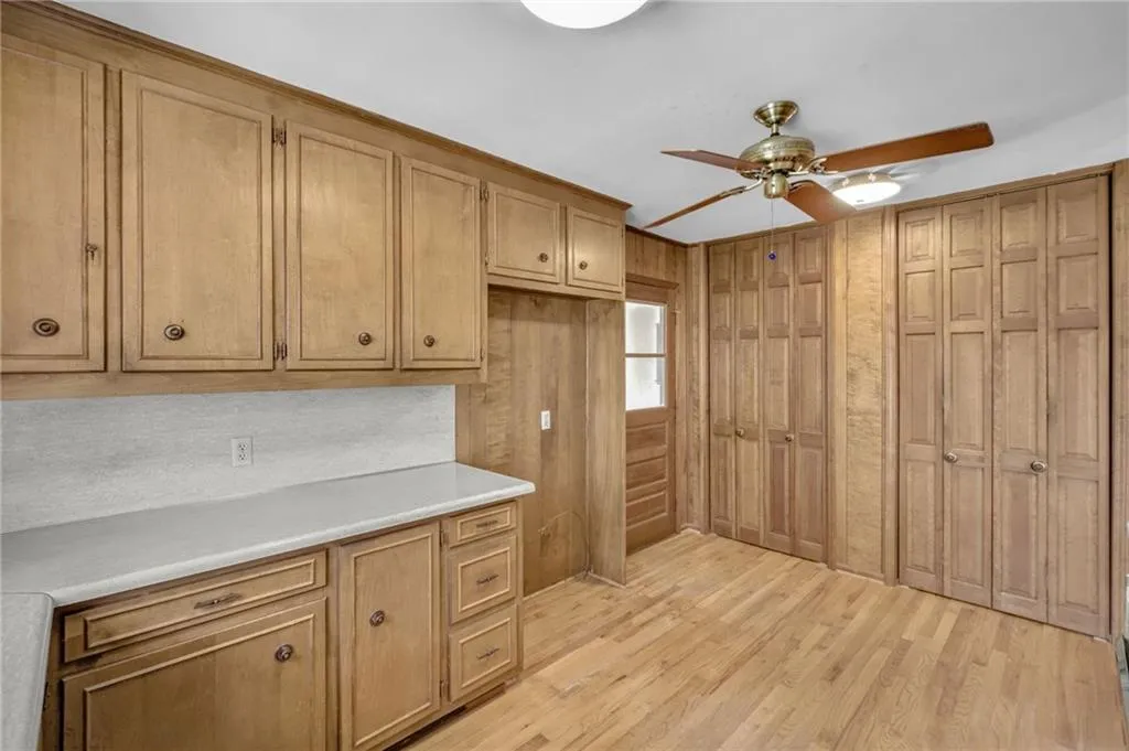Kitchen featuring ceiling fan, light wood-style flooring, light countertops, and wood walls