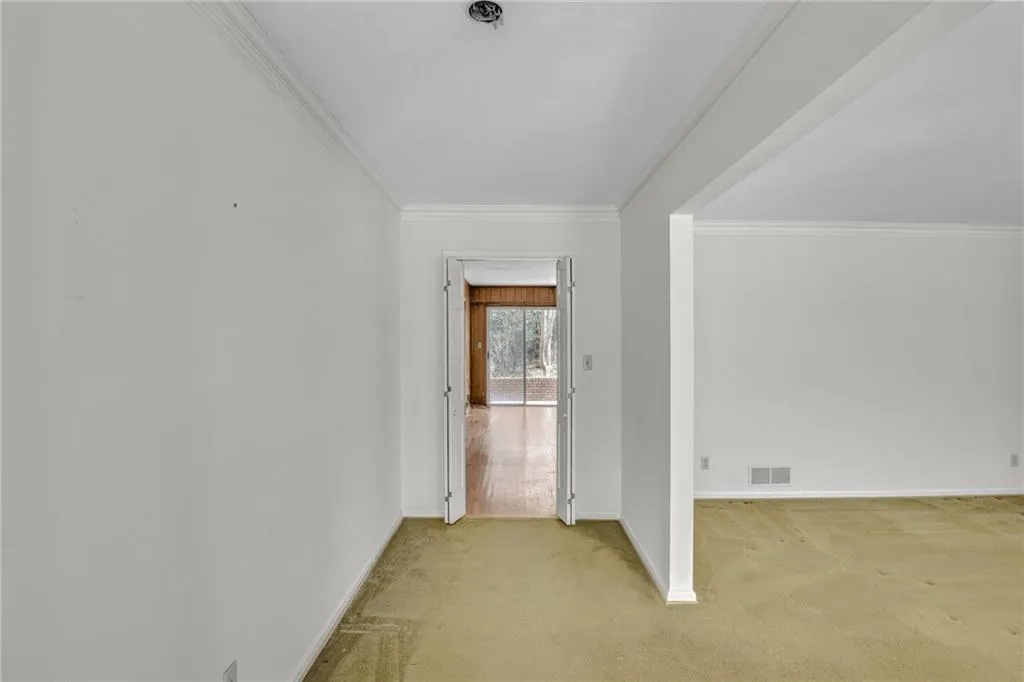 Additional living space with light colored carpet, visible vents, and baseboards