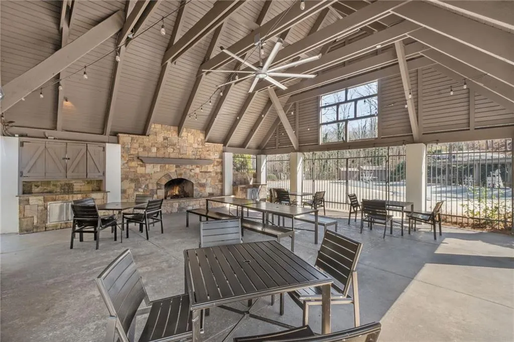 View of patio with an outdoor stone fireplace, ceiling fan, a gazebo, and fence