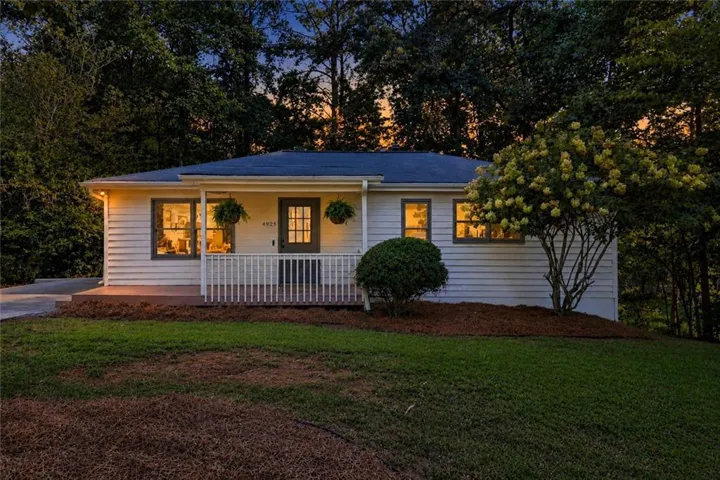 Siding exterior with a covered porch, white railing, and dark-paneled door