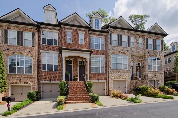Brick exterior with stone accents, dormer windows, attached garages, and an arched entryway