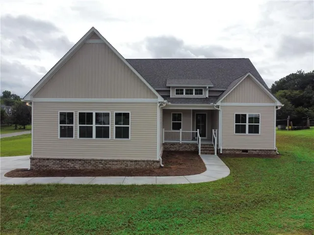 Contemporary home with beige siding, dark shingle roof, and a welcoming front porch