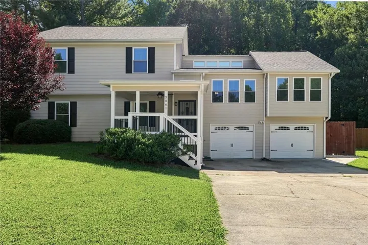 Two-story residence featuring light-colored siding, a covered front porch, and black window shutters