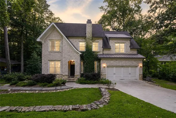 Brick exterior with a prominent chimney, dormer windows, and an attached two-car garage