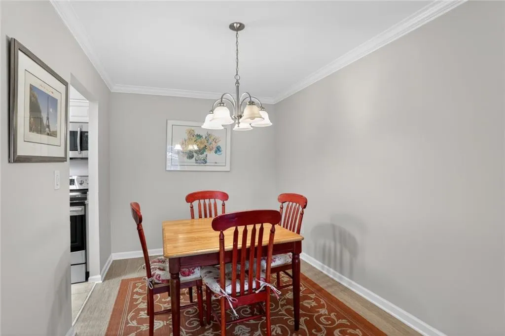 Dining room with light wood-style floors, crown molding, and a chandelier
