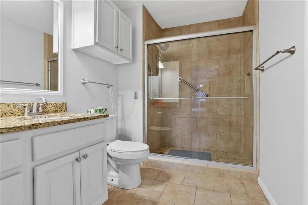 Full bath with vanity, a shower stall, and light tile patterned flooring