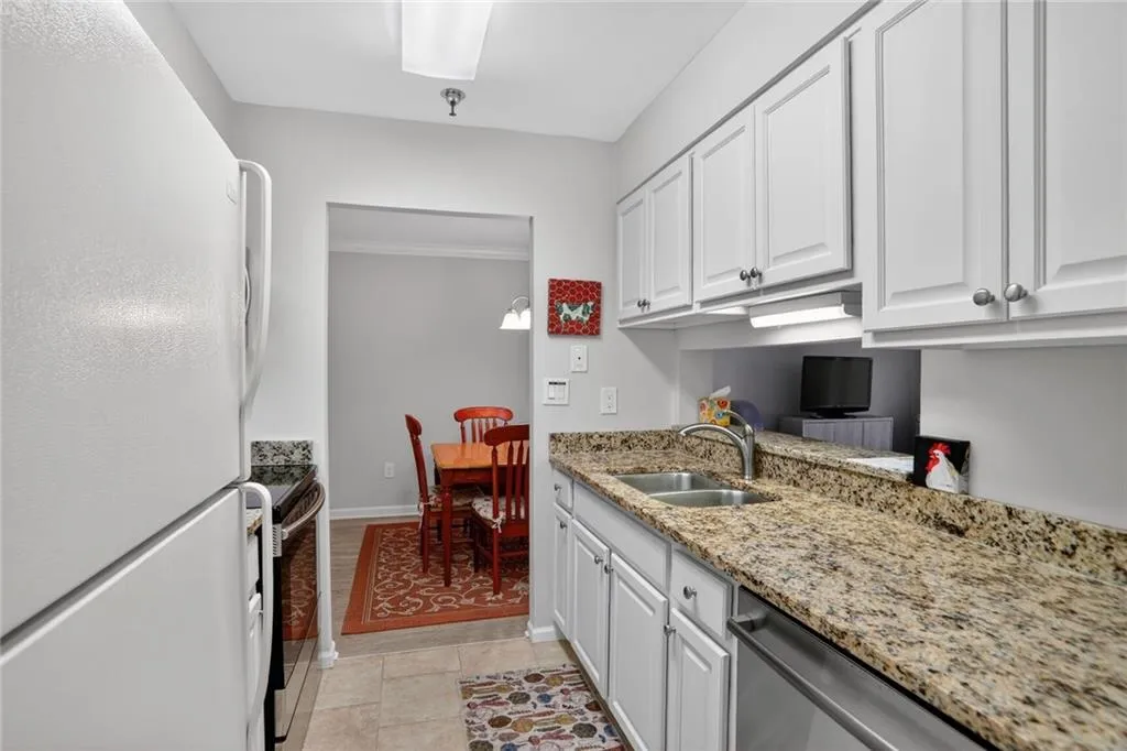 Kitchen with freestanding refrigerator, white cabinetry, light stone counters, stainless steel dishwasher, and electric stove