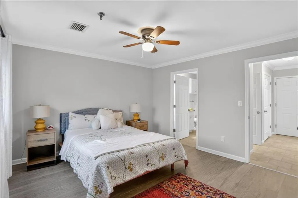 Bedroom with ornamental molding, a ceiling fan, and light wood finished floors