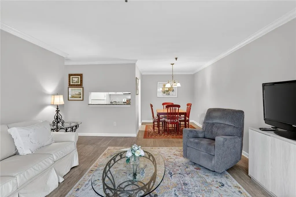 Living area featuring ornamental molding, a chandelier, and wood finished floors