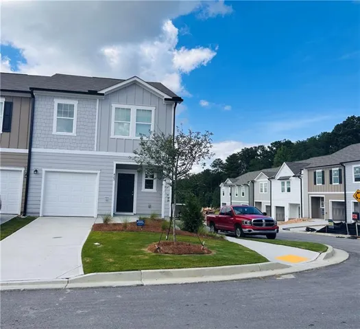 Modern townhome exterior featuring light gray siding, white trim, and a dark entry door