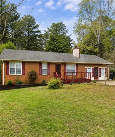 Brick exterior with a gray shingle roof and a red wood-finish deck