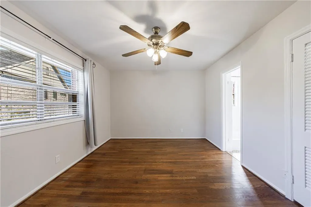Unfurnished room with dark wood-style flooring and a ceiling fan Unfurnished room with dark wood-style flooring and a ceiling fan