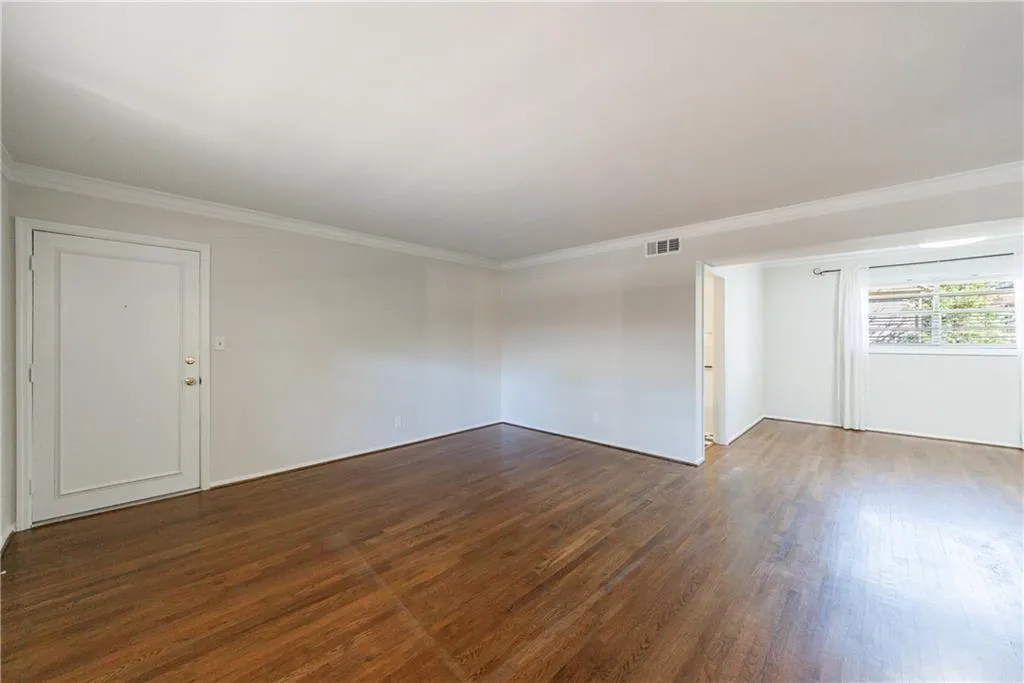 Unfurnished room featuring ornamental molding and dark wood finished floors Unfurnished room featuring ornamental molding and dark wood finished floors