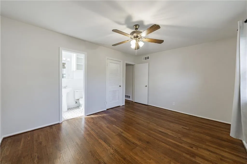 Unfurnished bedroom with dark wood-style floors, ceiling fan, and ensuite bathroom Unfurnished bedroom with dark wood-style floors, ceiling fan, and ensuite bathroom