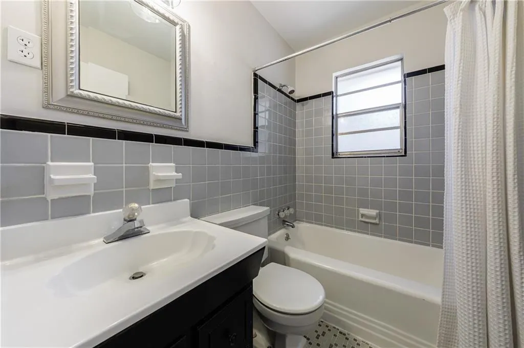Bathroom featuring shower / tub combo with curtain, tile walls, and vanity Bathroom featuring shower / tub combo with curtain, tile walls, and vanity