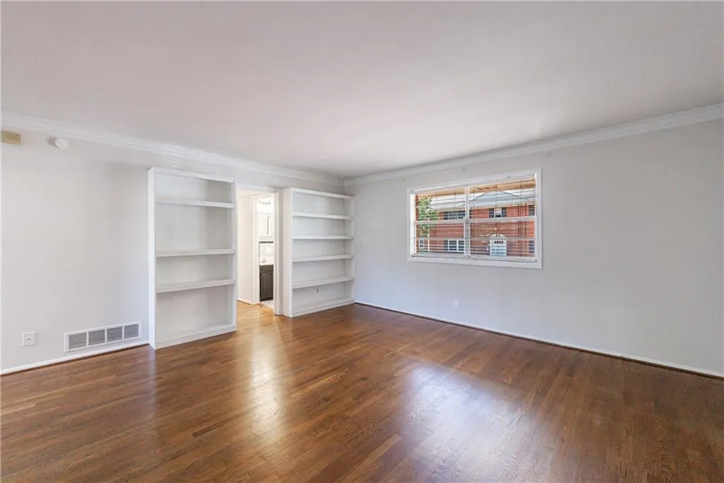 Spare room featuring ornamental molding and dark wood-style flooring Spare room featuring ornamental molding and dark wood-style flooring