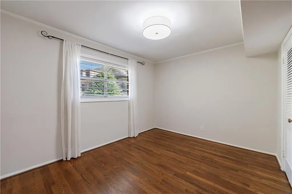 Spare room featuring crown molding and dark wood-style floors Spare room featuring crown molding and dark wood-style floors