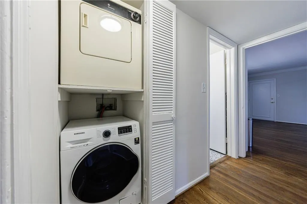 Laundry area with dark wood-style floors, stacked washer / dryer, and crown molding Laundry area with dark wood-style floors, stacked washer / dryer, and crown molding