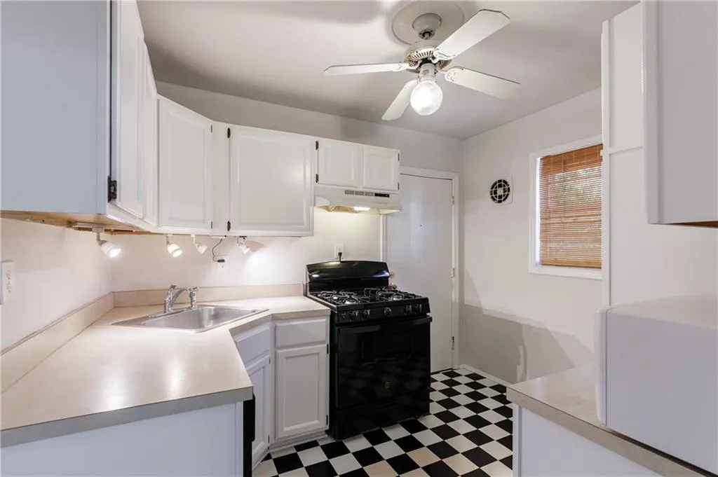 Kitchen with gas stove, white cabinetry, light countertops, light flooring, and under cabinet range hood Kitchen with gas stove, white cabinetry, light countertops, light flooring, and under cabinet range hood