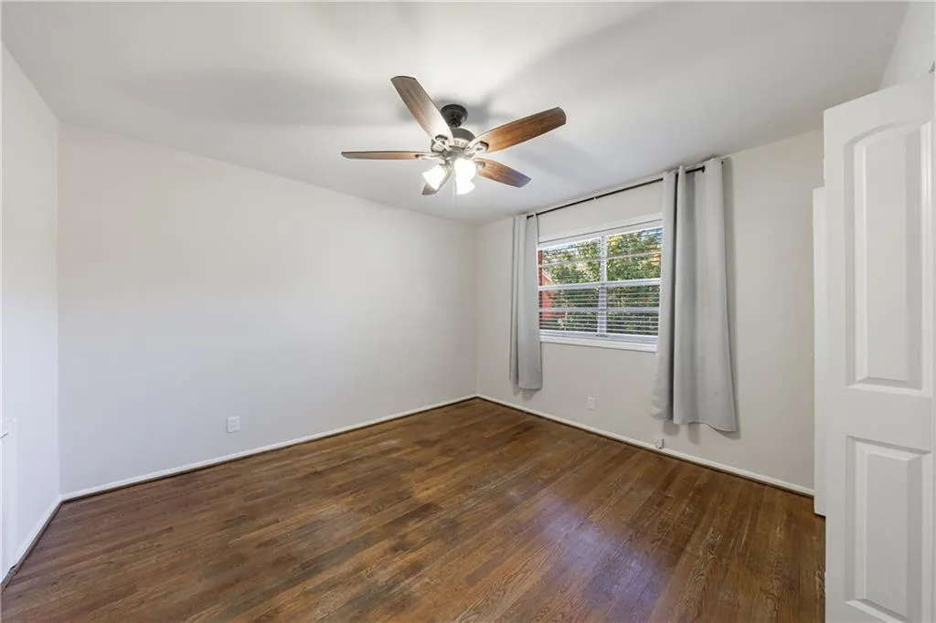 Empty room featuring dark wood-style flooring and ceiling fan Empty room featuring dark wood-style flooring and ceiling fan