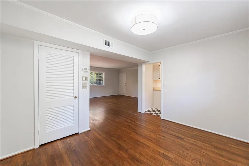 Spare room featuring ornamental molding and dark wood-style flooring Spare room featuring ornamental molding and dark wood-style flooring