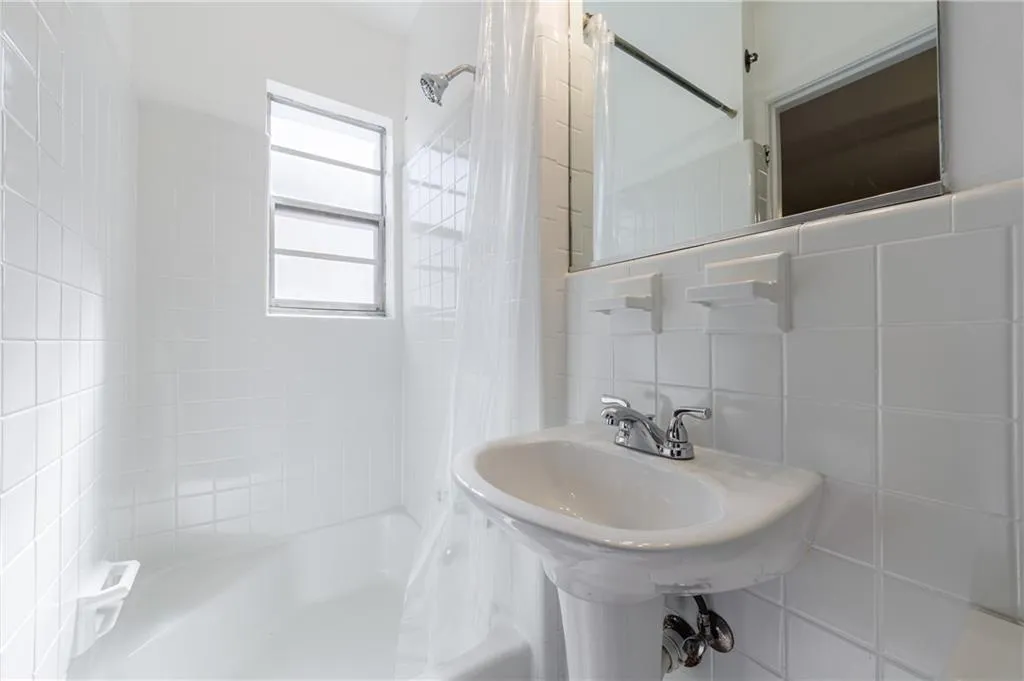 Bathroom with shower / bath combo with shower curtain, tile walls, and tasteful backsplash Bathroom with shower / bath combo with shower curtain, tile walls, and tasteful backsplash