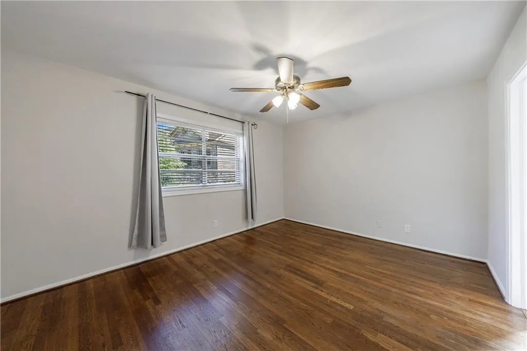 Unfurnished room with dark wood-style flooring and a ceiling fan Unfurnished room with dark wood-style flooring and a ceiling fan