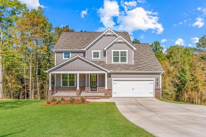 Two-story residence featuring grey siding, a covered front porch with brick column bases, a two-car garage, and a concrete driveway