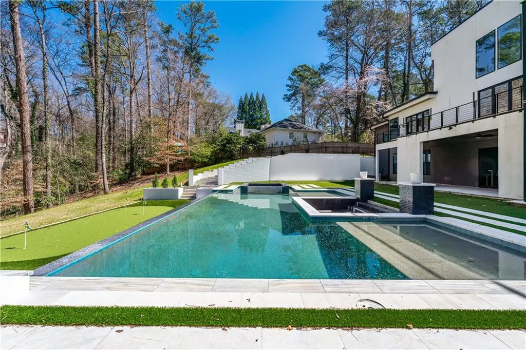 View of pool featuring a patio, a jacuzzi, a putting green, a fenced backyard, and a balcony