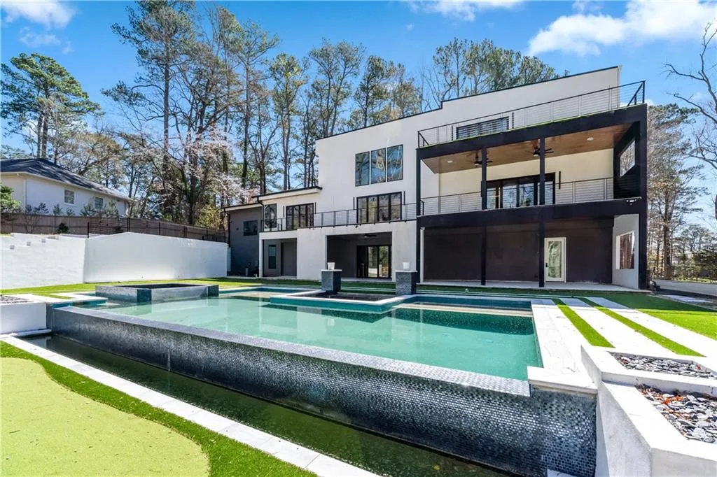 Back of house featuring an in-ground hot tub, stucco siding, a balcony, a patio, and a ceiling fan