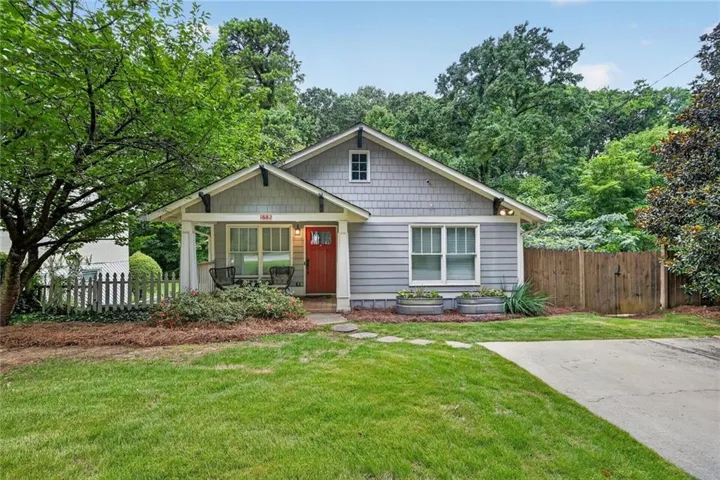 Craftsman-style facade with a prominent porch, gray siding, and an inviting red entry door
