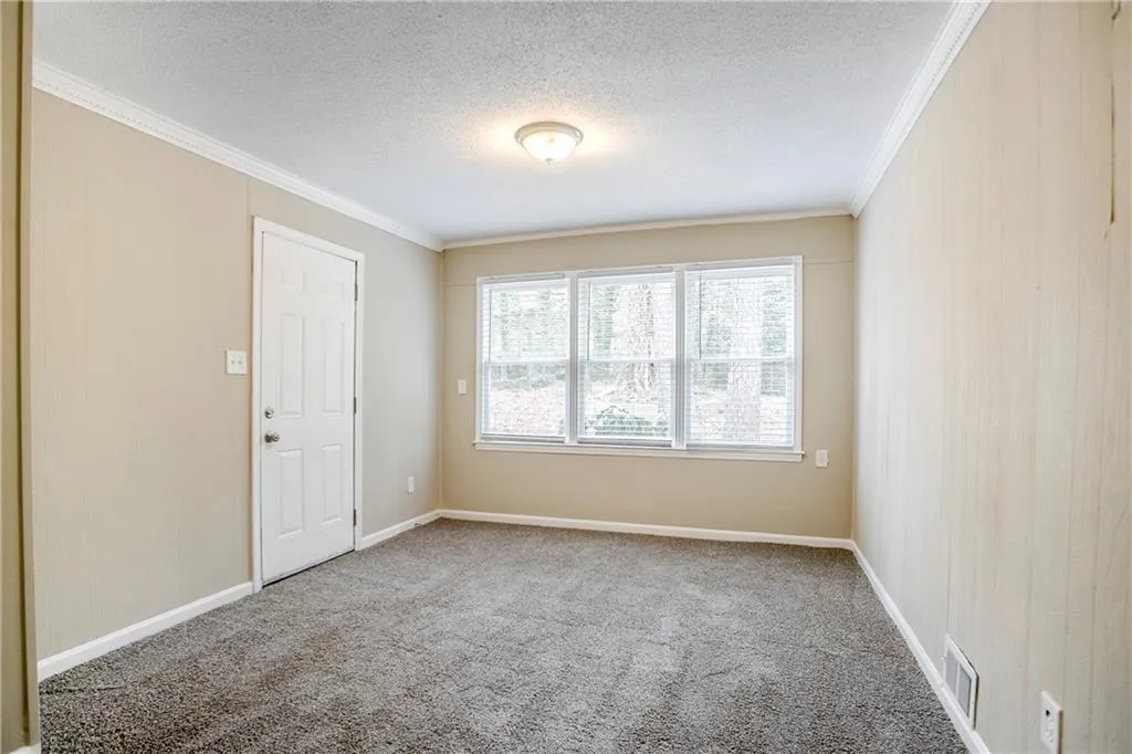 Carpeted empty room with a textured ceiling and ornamental molding