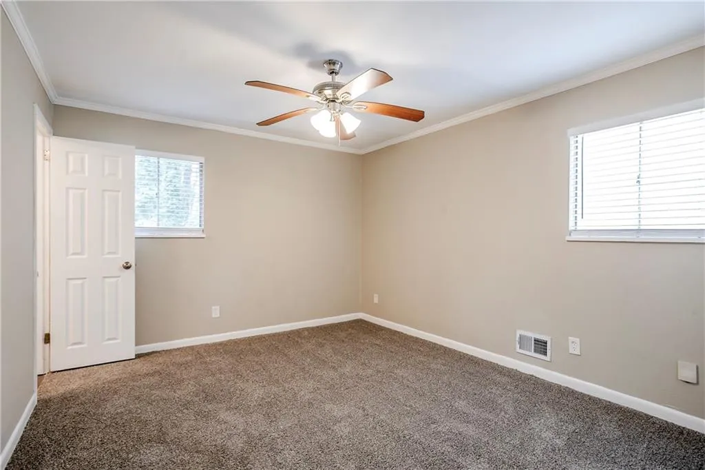 Empty room with ceiling fan, carpet, and ornamental molding