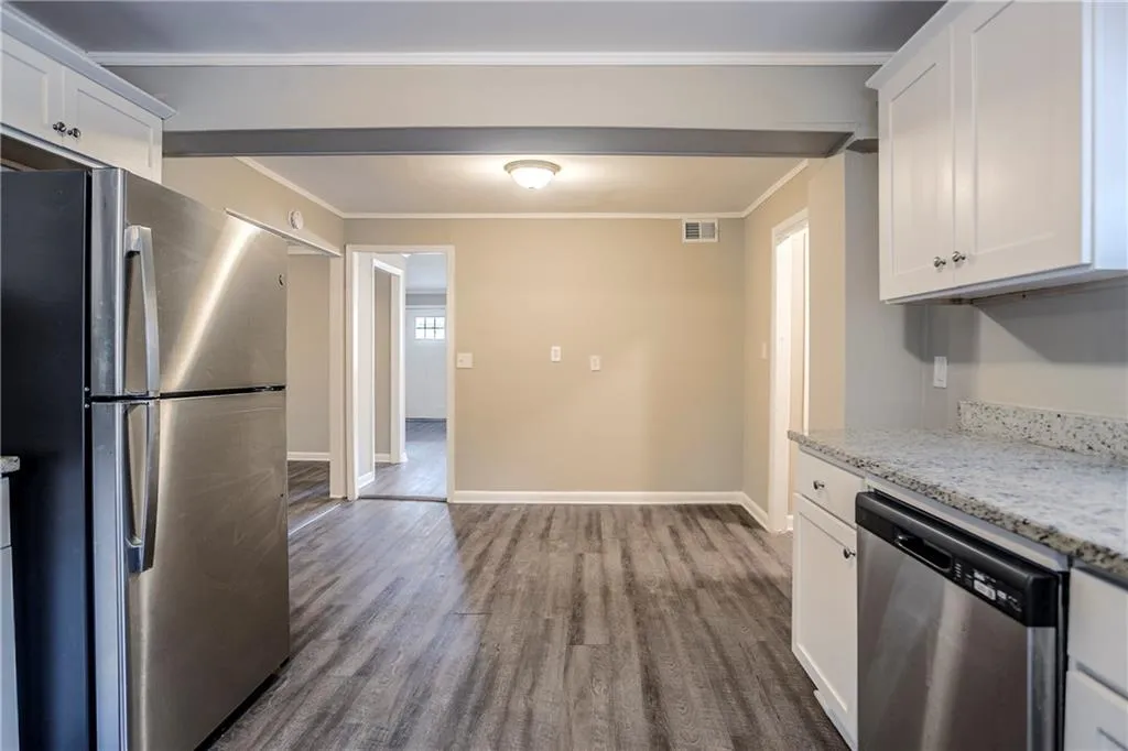 Kitchen featuring light stone counters, white cabinets, hardwood / wood-style flooring, and stainless steel appliances