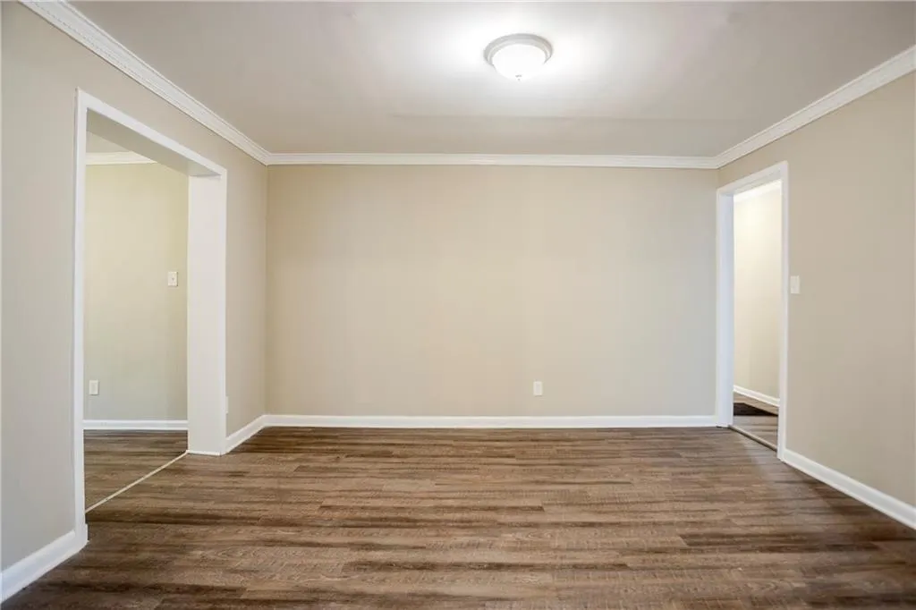 Empty room featuring dark hardwood / wood-style flooring and ornamental molding