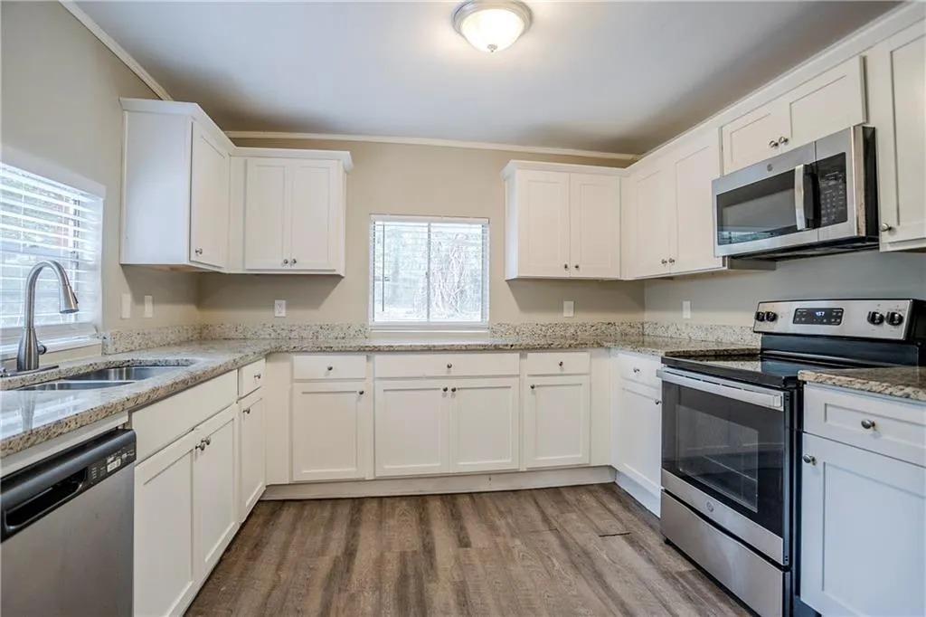 Kitchen featuring sink, white cabinetry, light stone countertops, and appliances with stainless steel finishes