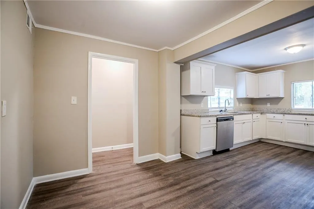 Kitchen featuring dishwasher, white cabinetry, light stone counters, and dark hardwood / wood-style floors