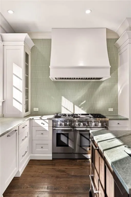 Kitchen featuring double oven range, custom range hood, white cabinetry, dark wood-style flooring, and recessed lighting