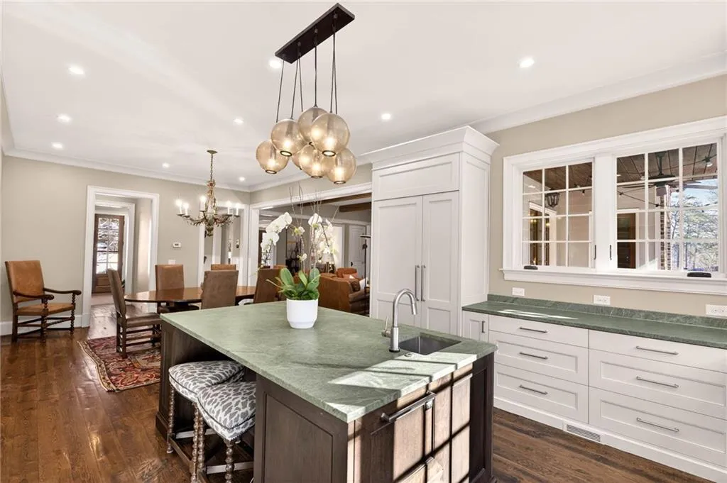 Kitchen featuring a kitchen breakfast bar, an island with sink, recessed lighting, white cabinets, and ornamental molding