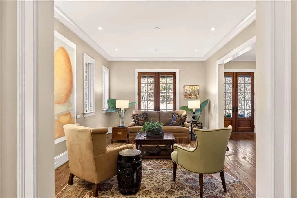 Living area with french doors, wood finished floors, ornamental molding, plenty of natural light, and recessed lighting