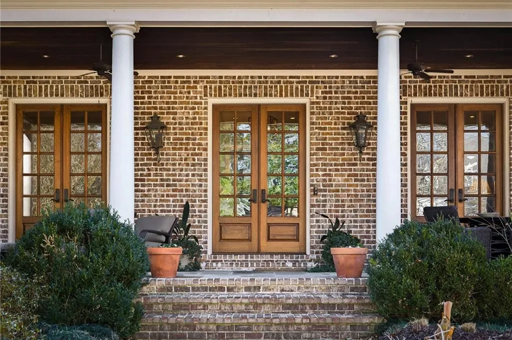 Doorway to property featuring french doors, a porch, and brick siding