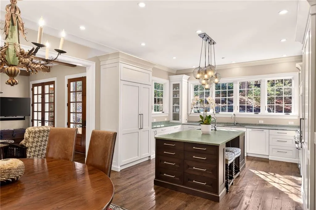 Kitchen featuring a chandelier, dark brown cabinetry, ornamental molding, glass insert cabinets, and plenty of natural light