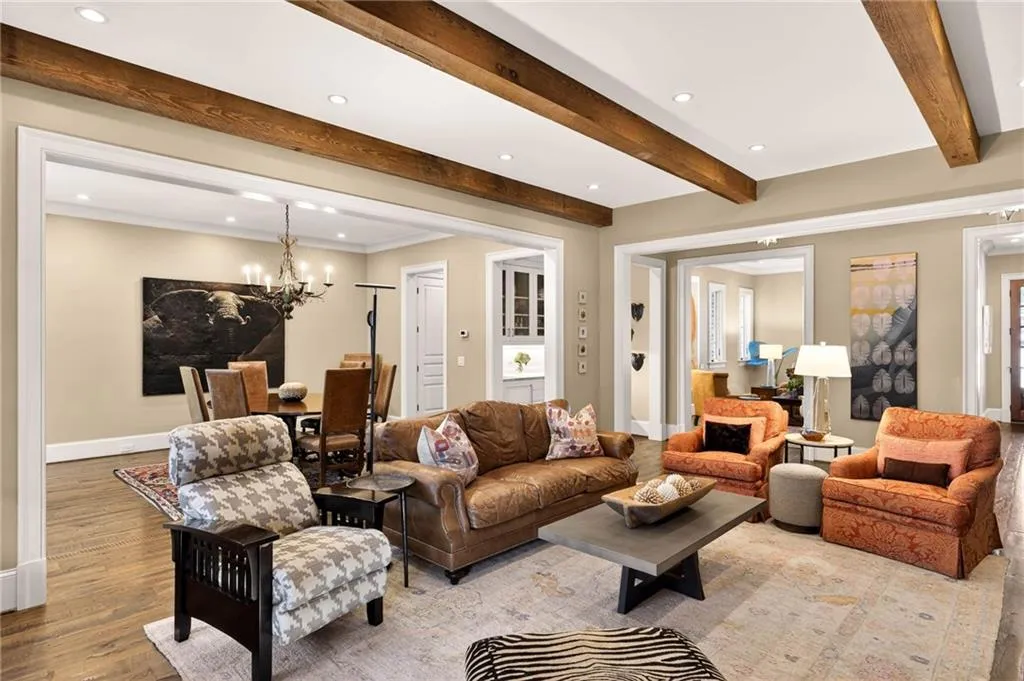 Living room with recessed lighting, a chandelier, wood finished floors, beamed ceiling, and ornamental molding