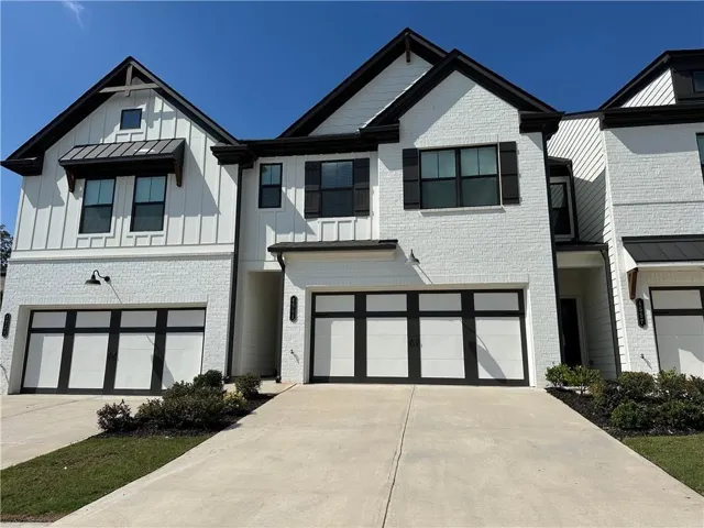Modern two-story residence featuring a clean white brick and board-and-batten exterior with black-trimmed windows and gabled rooflines