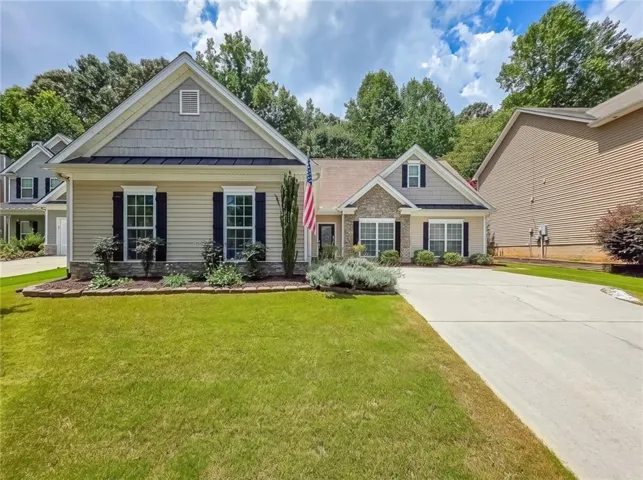 Two-tone siding exterior featuring a natural stone accent facade, black louvered shutters, and a concrete driveway