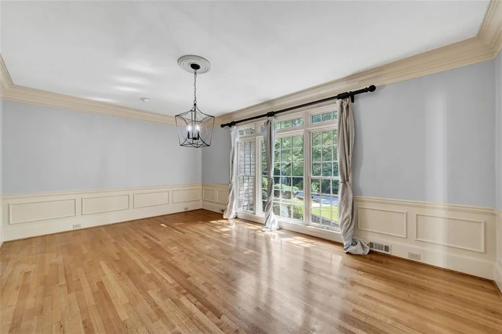 Unfurnished room featuring a barn door, crown molding, light wood-type flooring, and a chandelier