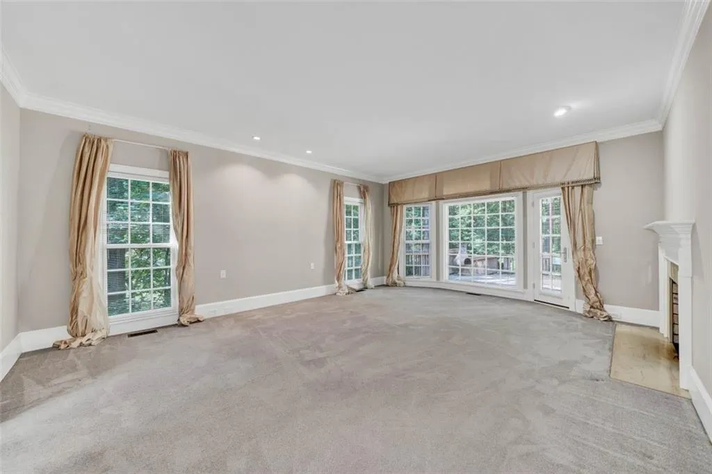 Unfurnished living room with a healthy amount of sunlight, ornamental molding, and carpet floors