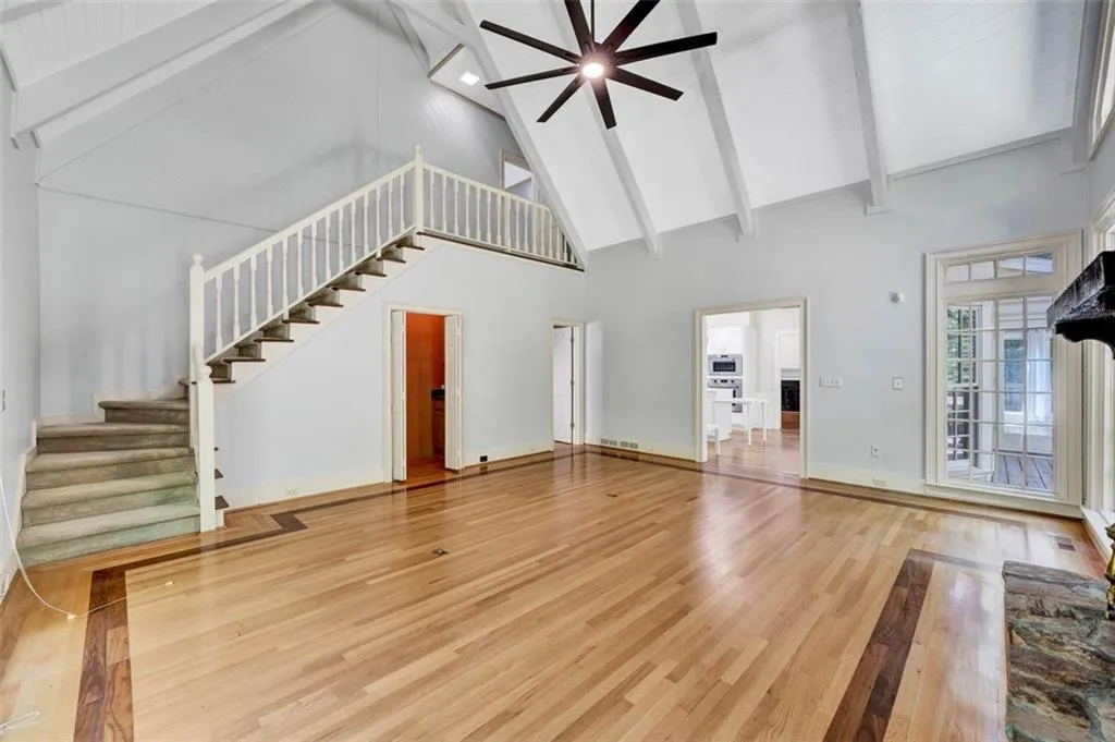 Unfurnished living room featuring beam ceiling, high vaulted ceiling, hardwood / wood-style flooring, and ceiling fan